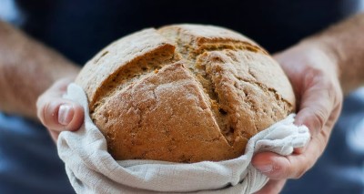 person serving a fresh-baked round loaf of bread