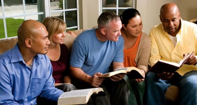 Five adults, black and white, with open bibles in their hands, lean in for study