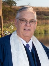 Carl K. Ellis, smiling, wearing blue clergy robe and white stole